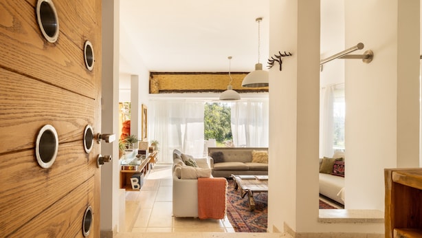 Een moderne woonkamer met een bank, salontafel en decoratieve kussens. Een houten kast met ronde handgrepen is links zichtbaar.
