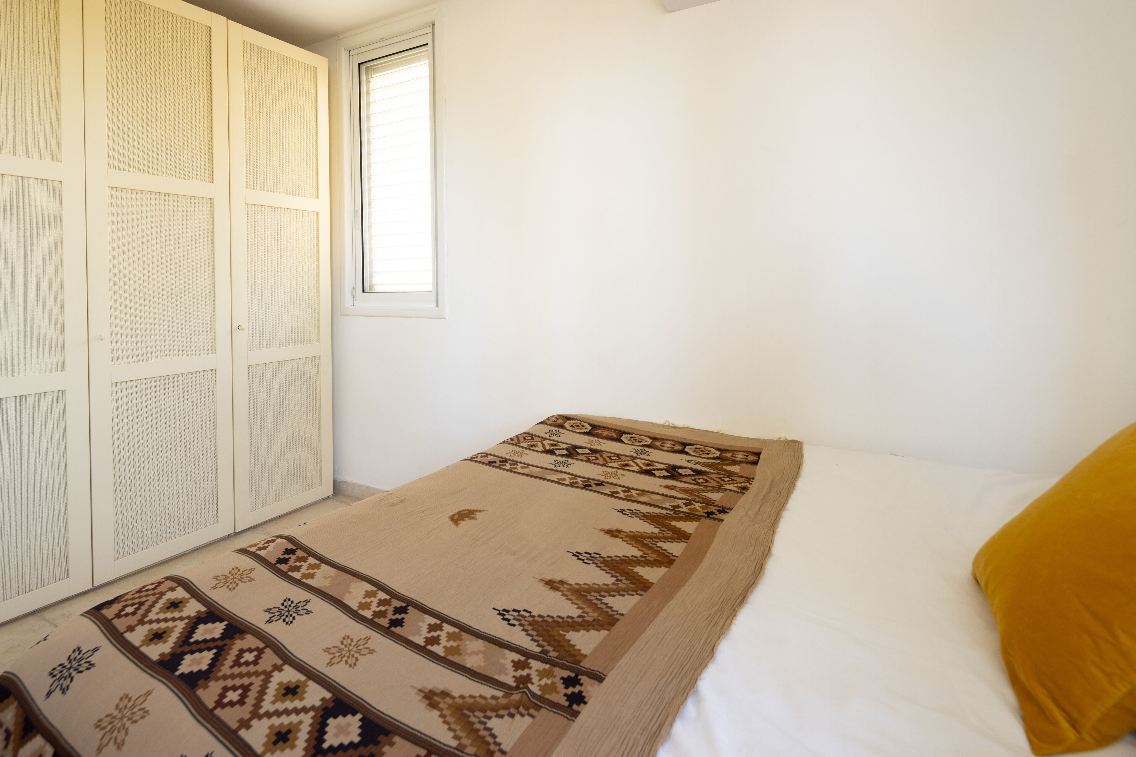 Een slaapkamer met een bed, een raam en een kledingkast.