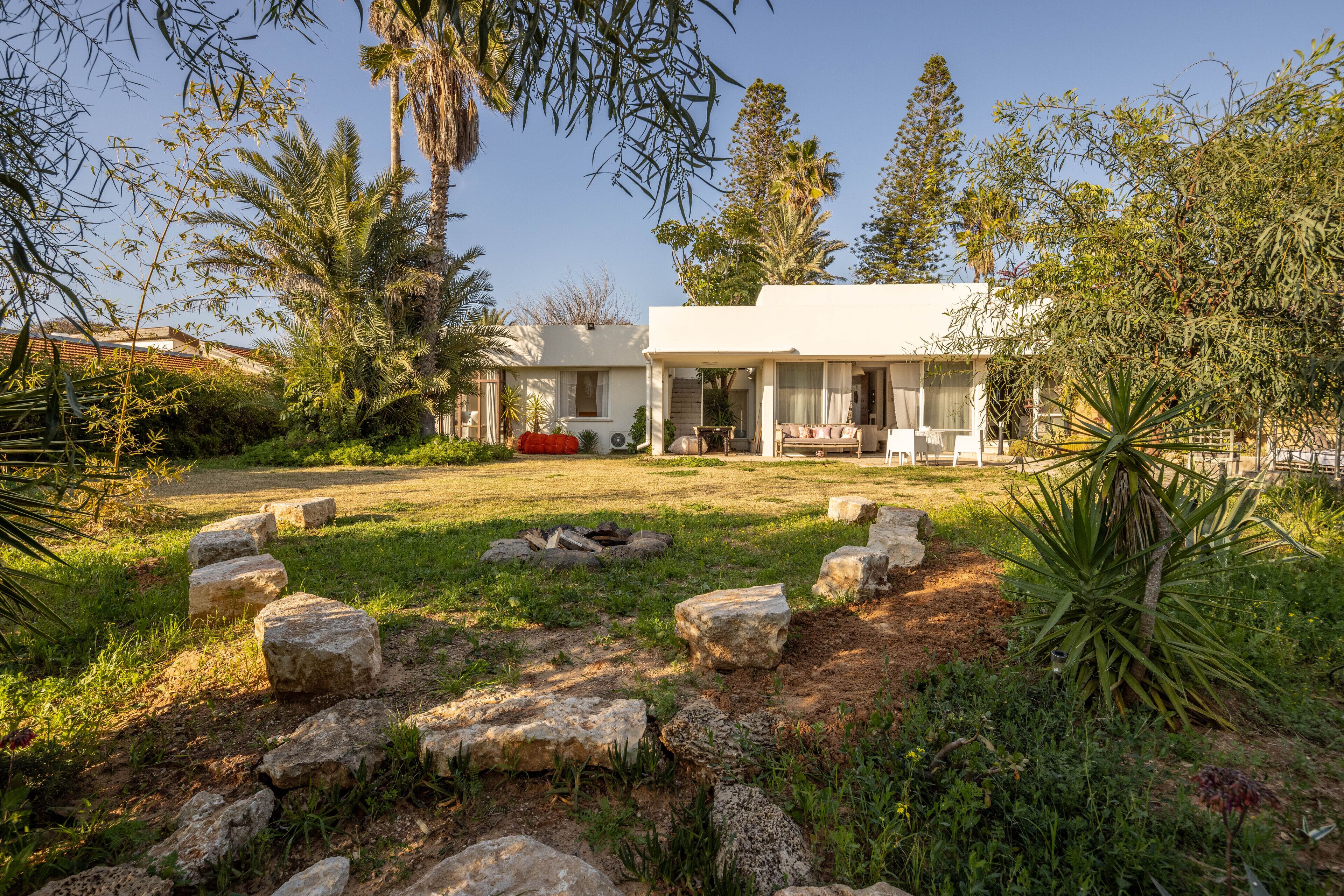 Uma casa com jardim, lareira e área de estar ao ar livre.