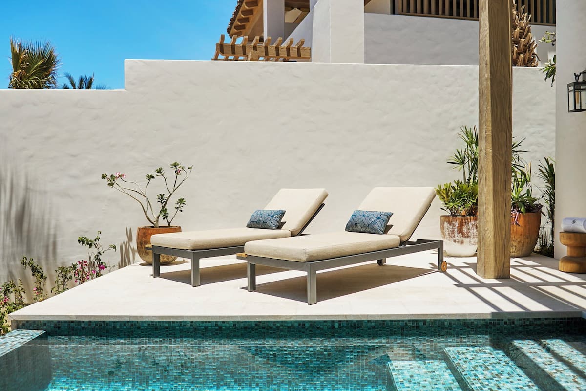 A poolside area with two lounge chairs and a pergola.