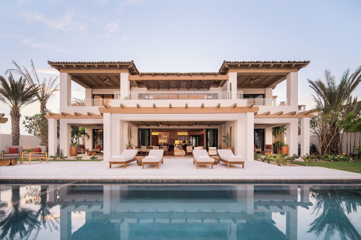 A modern two-story house with a pool, outdoor seating, and a patio area.
