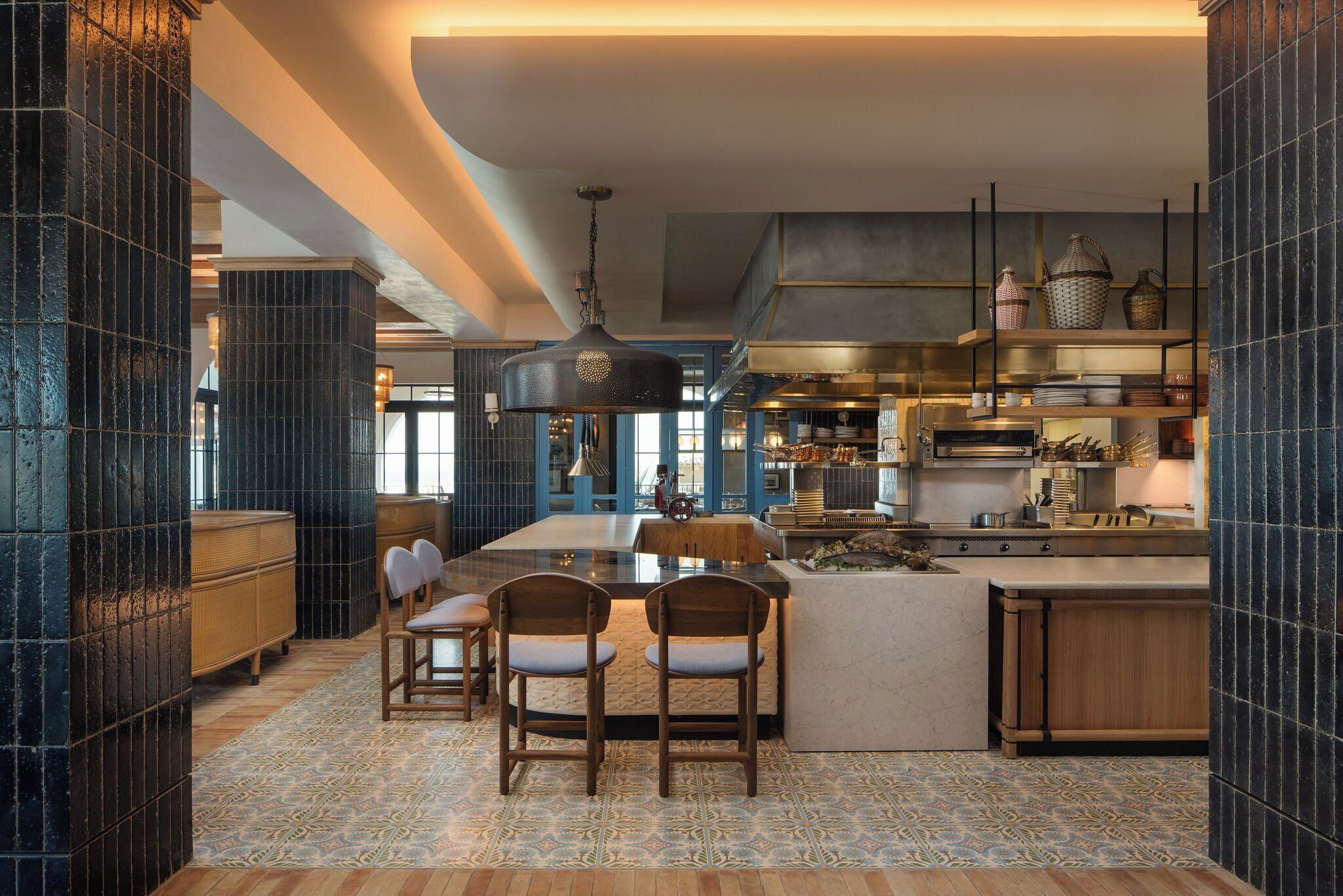 Uma cozinha moderna com uma ilha central, banquetas de bar e uma janela grande.