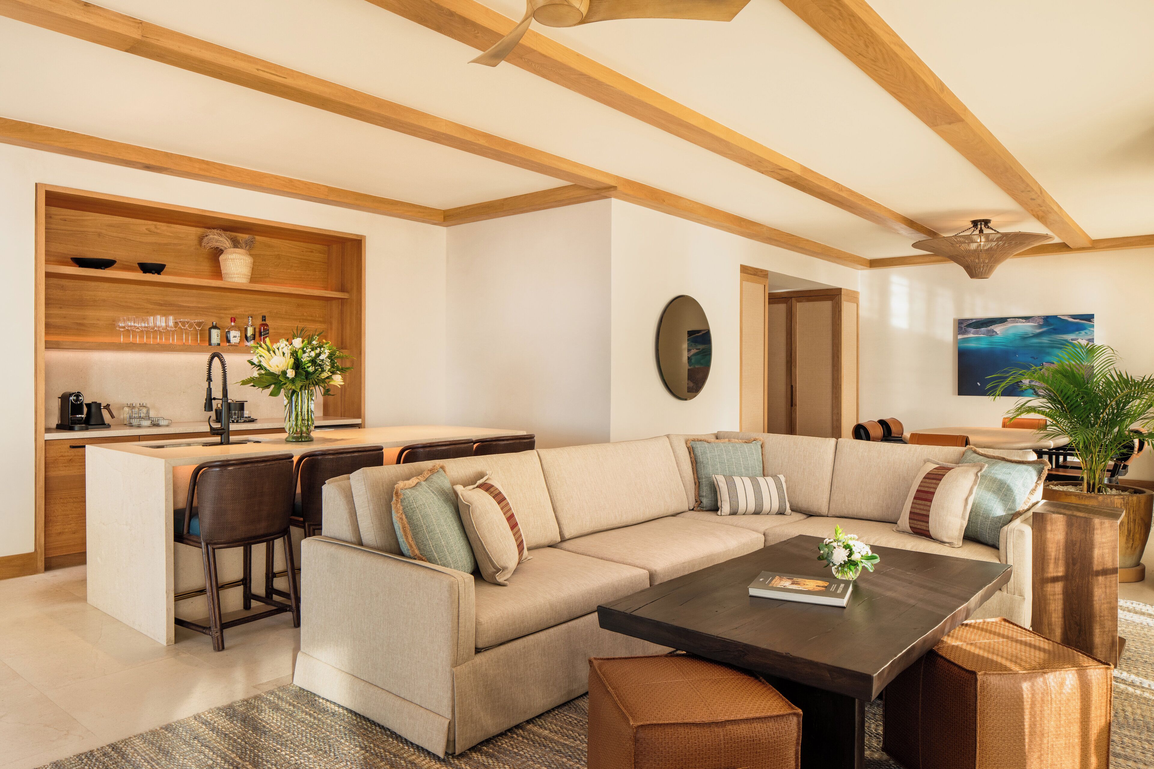 A modern living room with a large sectional sofa, a coffee table, and a kitchen area with a built-in island.