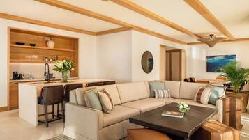 A modern living room with a large sectional sofa, a coffee table, and a kitchen area with a built-in island.