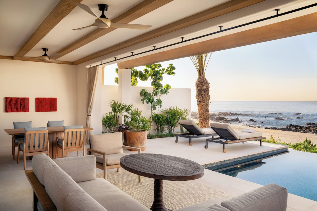 A modern outdoor lounge area with a pool, seating, and a view of the ocean.