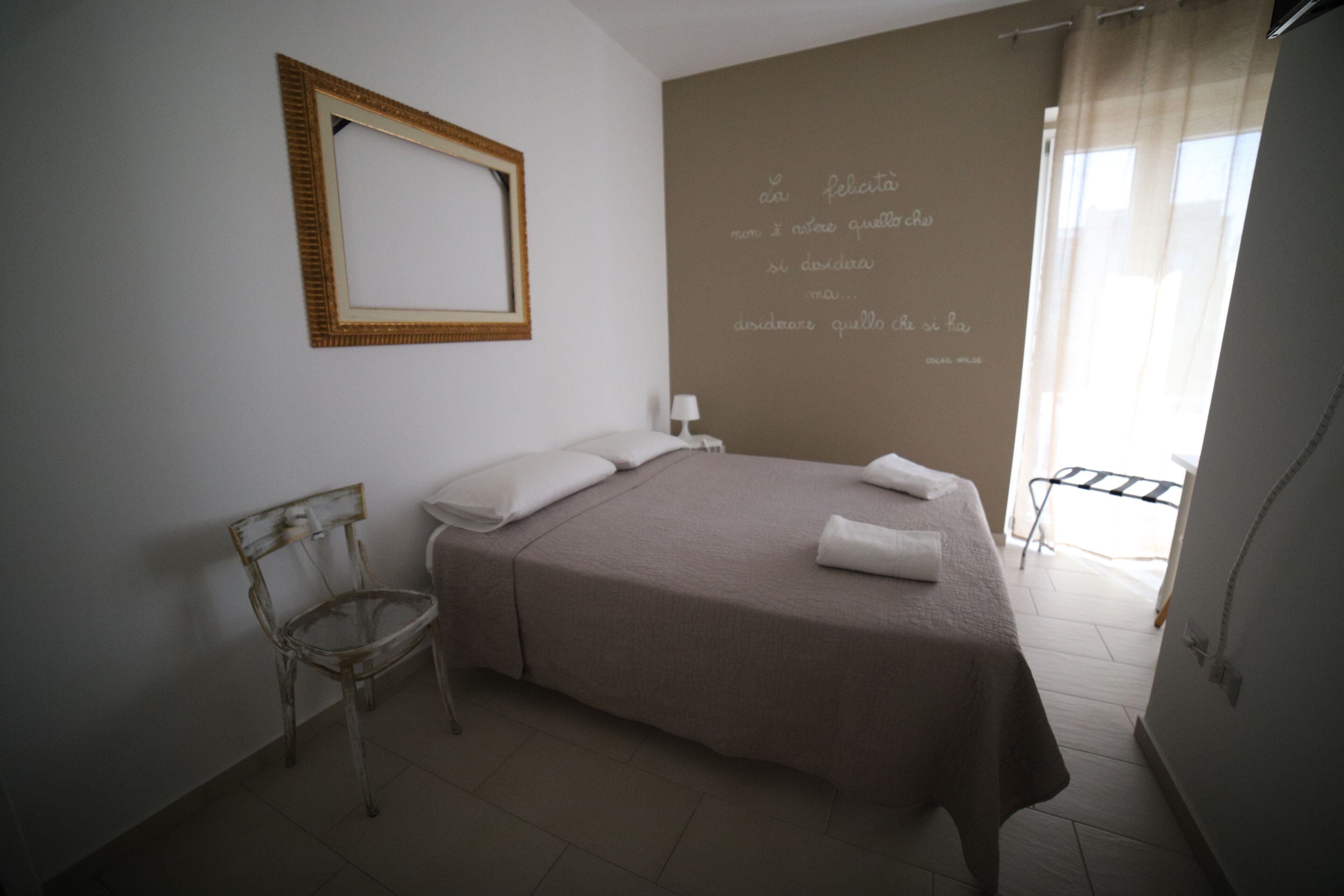 Una camera da letto con un letto, una sedia, un comodino e una parete con un messaggio.
