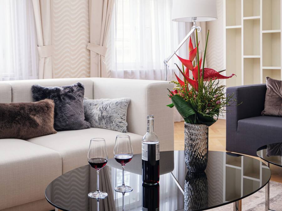 A modern living room with a glass coffee table, a sofa, and a side table with a vase of flowers.