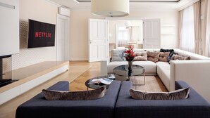 A modern living room with a sectional sofa, a coffee table, and a flat-screen TV mounted on the wall. - R16 Residences Prague (Prague)