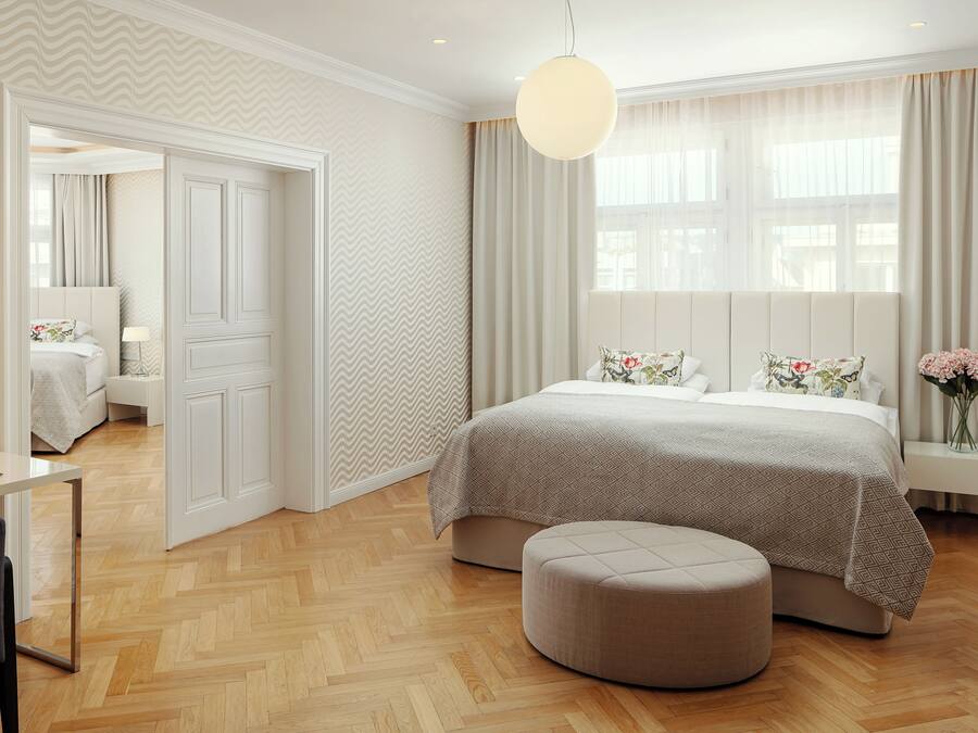 Une chambre à coucher moderne avec un grand lit, une table de chevet, une chaise et une fenêtre avec des rideaux.
