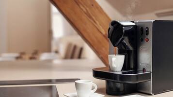 Una cafetera moderna con una taza de café sobre una mesa.