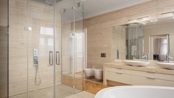 A modern bathroom with a glass-enclosed shower, a freestanding bathtub, and a large mirror above the sink.