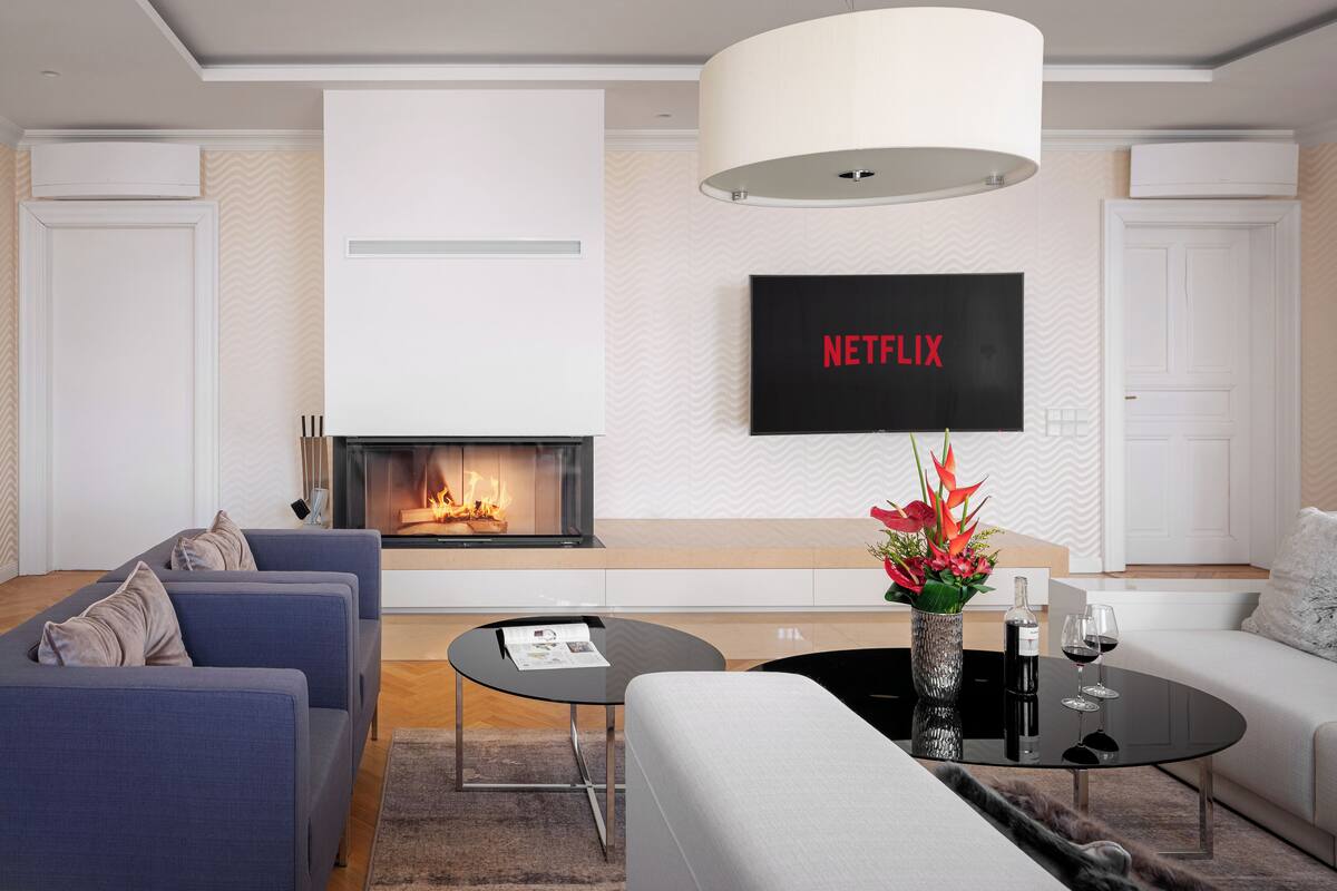 Una sala moderna con chimenea, un televisor de pantalla plana montado encima y un conjunto de sofás.