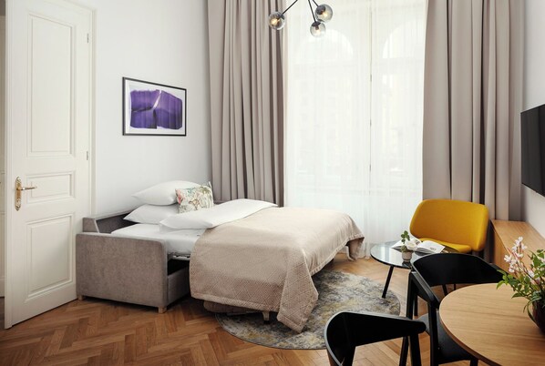 Una habitación de hotel moderna con una cama, un escritorio pequeño, una silla y un televisor.
