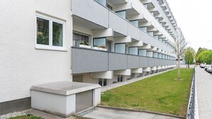 A modern multi-story building with balconies, a flat roof, and a paved walkway. - Centerroom München City (Munich)