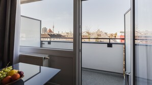 A room with a view of a cityscape, a table with fruit, and a window with a view of buildings and a tower. - Centerroom München City (Munich)