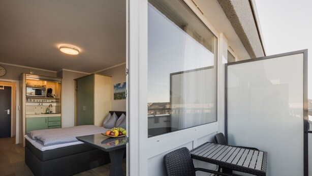 Apartament modern amb cuineta, zona de menjador amb taula i cadires, i un balcó amb vistes.