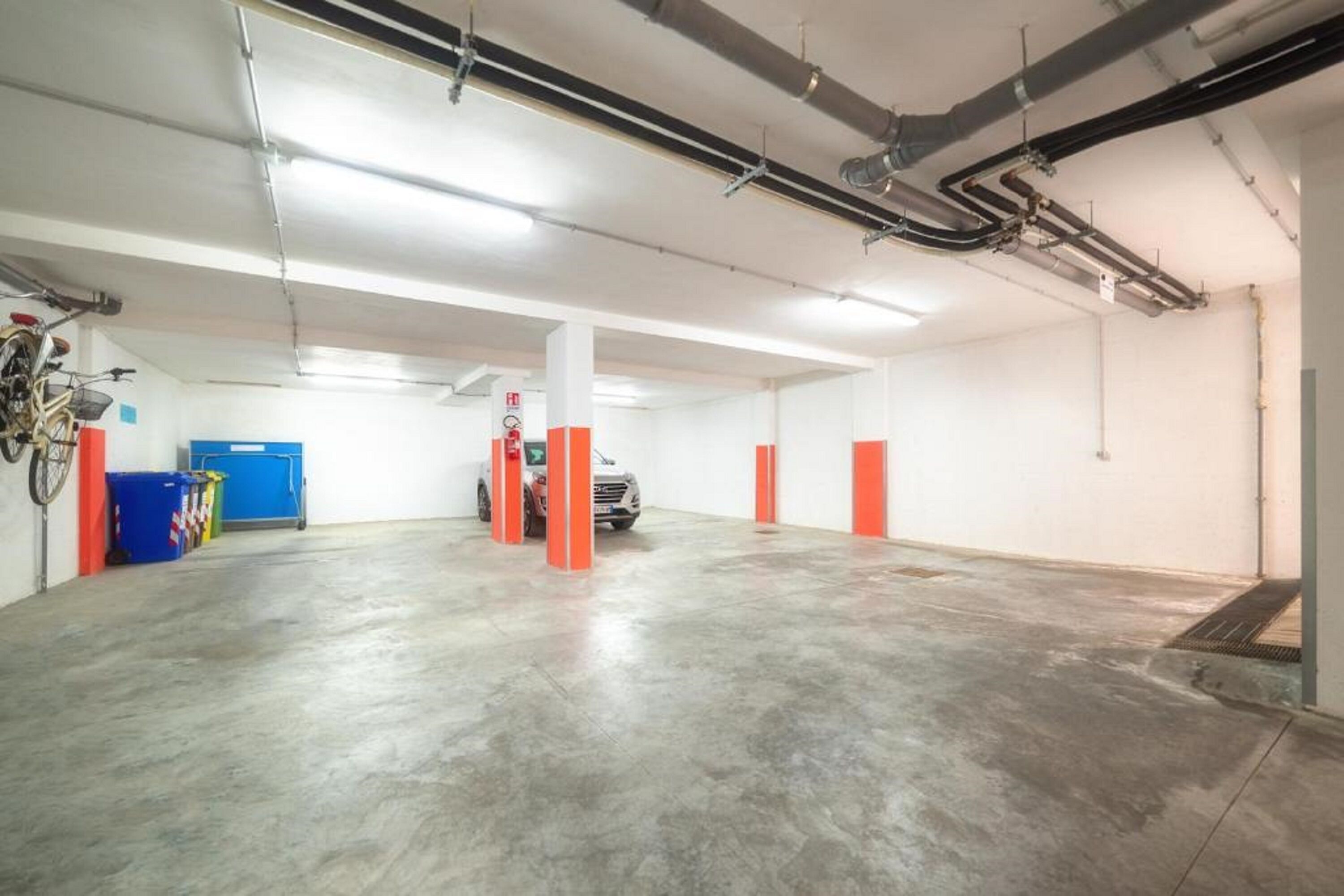 A spacious indoor parking area with concrete floors and white walls.