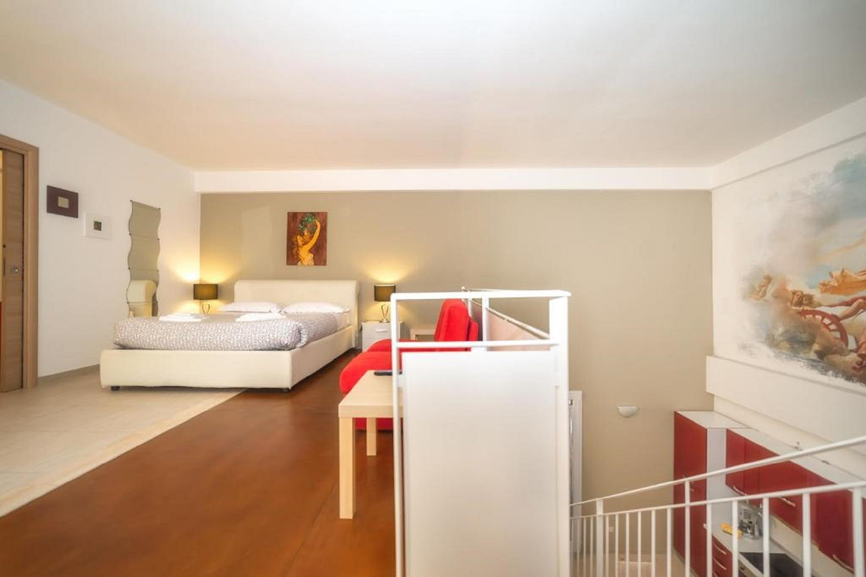 Un dormitorio con cama, mesita de noche, lámpara y un cuadro en la pared.