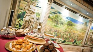 A buffet table with various pastries and a mural in the background. - Il Cortile delle Esperidi (Lecce)