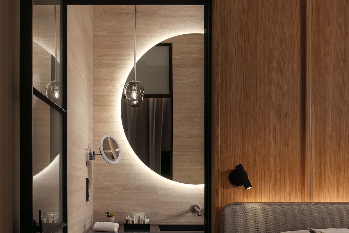 Une salle de bain moderne avec un meuble-lavabo en bois, un miroir rond et une douche intégrée.