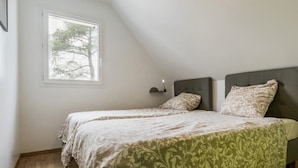 Une chambre avec deux lits, une fenêtre et une table de chevet avec une lampe.