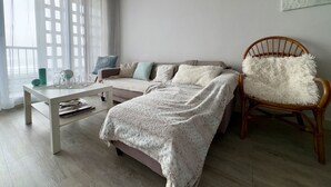 A cozy bedroom with a bed, a wooden chair, a table, and a painting of a boat on the wall.
