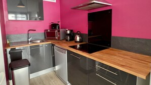 A modern kitchen with stainless steel appliances, a wooden countertop, and a black and pink color scheme.