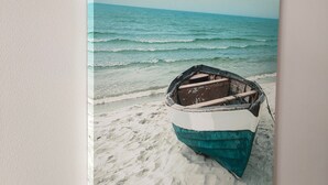 A boat on a sandy beach with the ocean in the background.