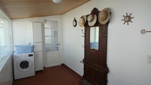 A laundry room with a washing machine, a drying rack, and a wooden door with hats on it.