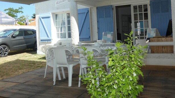 A house with a covered patio, white furniture, and blue shutters.