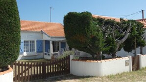 A residential building with a tiled roof, a fenced yard, and a well-maintained garden.