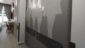 A hallway with a modern design, featuring a wall-mounted artwork of silhouetted figures, a wooden desk, and a chair. - "Dione" Luxury Business Suite in the Heart of Athens (Athina)