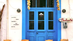 A blue door with a sign above it, two wooden chairs, and a table in front. - "Dione" Luxury Business Suite in the Heart of Athens (Athina)