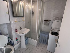 A bathroom with a shower, toilet, sink, and a mirror. - Cozy Studio with Pool Access - Sleeps 4, Close to Amenities (Port Camargue)