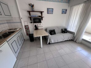 A compact kitchen with a dining area, a microwave, a sink, and a small table.