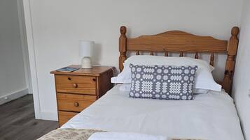 A neatly made bed with a patterned bedspread, a pillow with a geometric design, and a bedside table with a lamp.