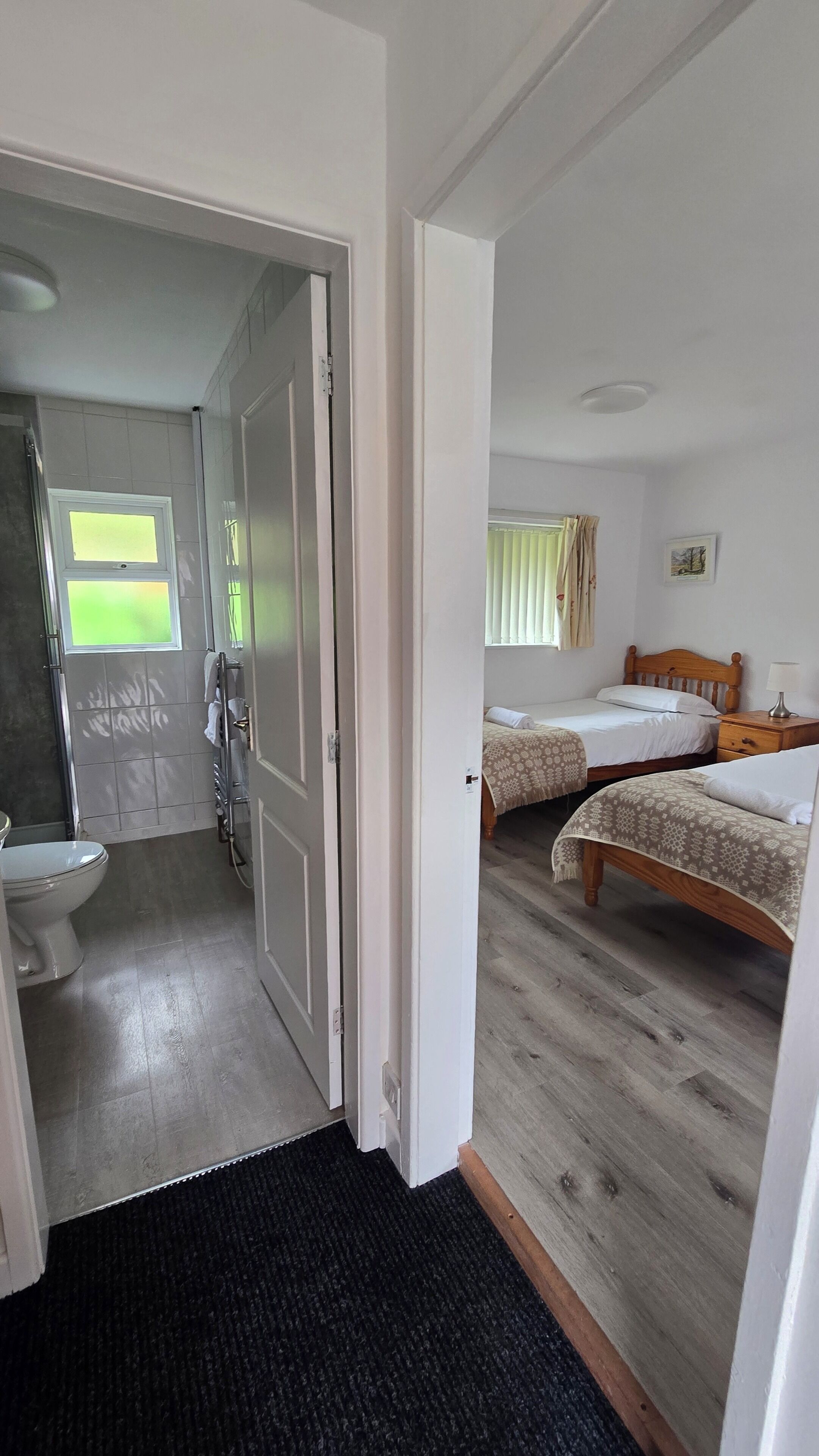 Een kamer met twee bedden, een badkamer met toilet en een deur naar een andere kamer.