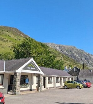 A building with a sign that reads 'Cross Roads.' There are cars parked in front. - Snowdonia Mountain Lodge (Bangor)