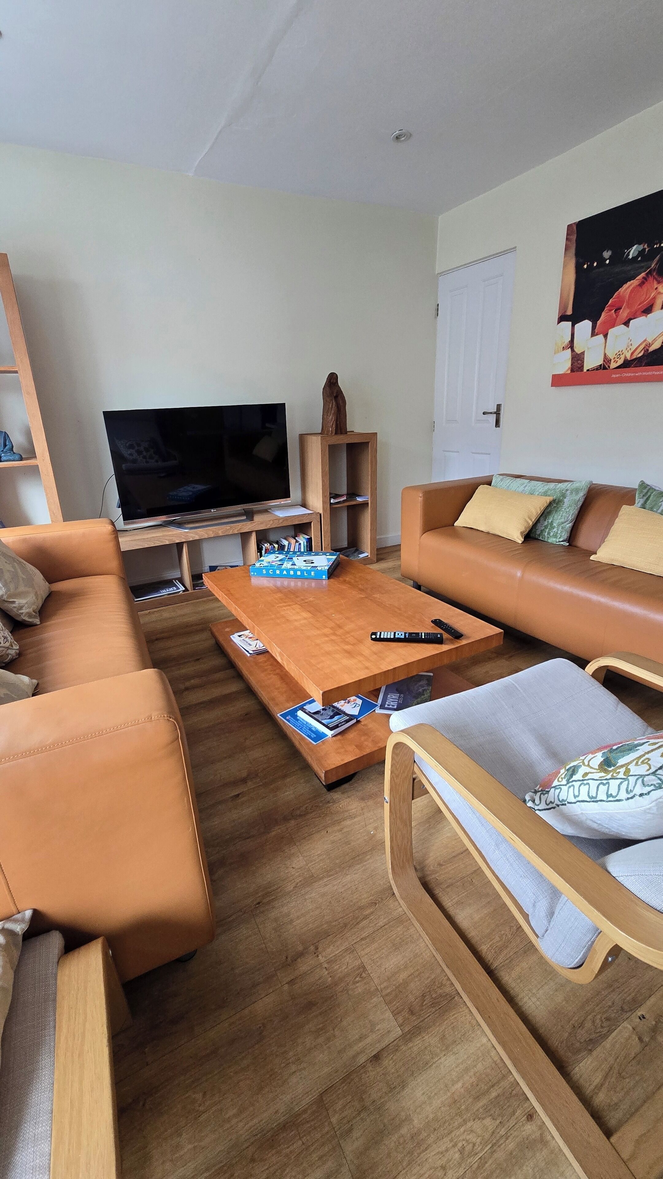A living room with a sofa, coffee table, TV, and a wooden shelf.
