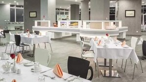 A modern dining area with round tables, white tablecloths, and neatly arranged cutlery.
