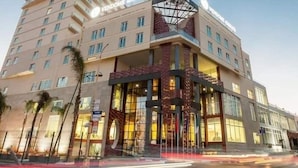 A multi-story hotel with a modern design, featuring a prominent glass facade and a rooftop terrace.