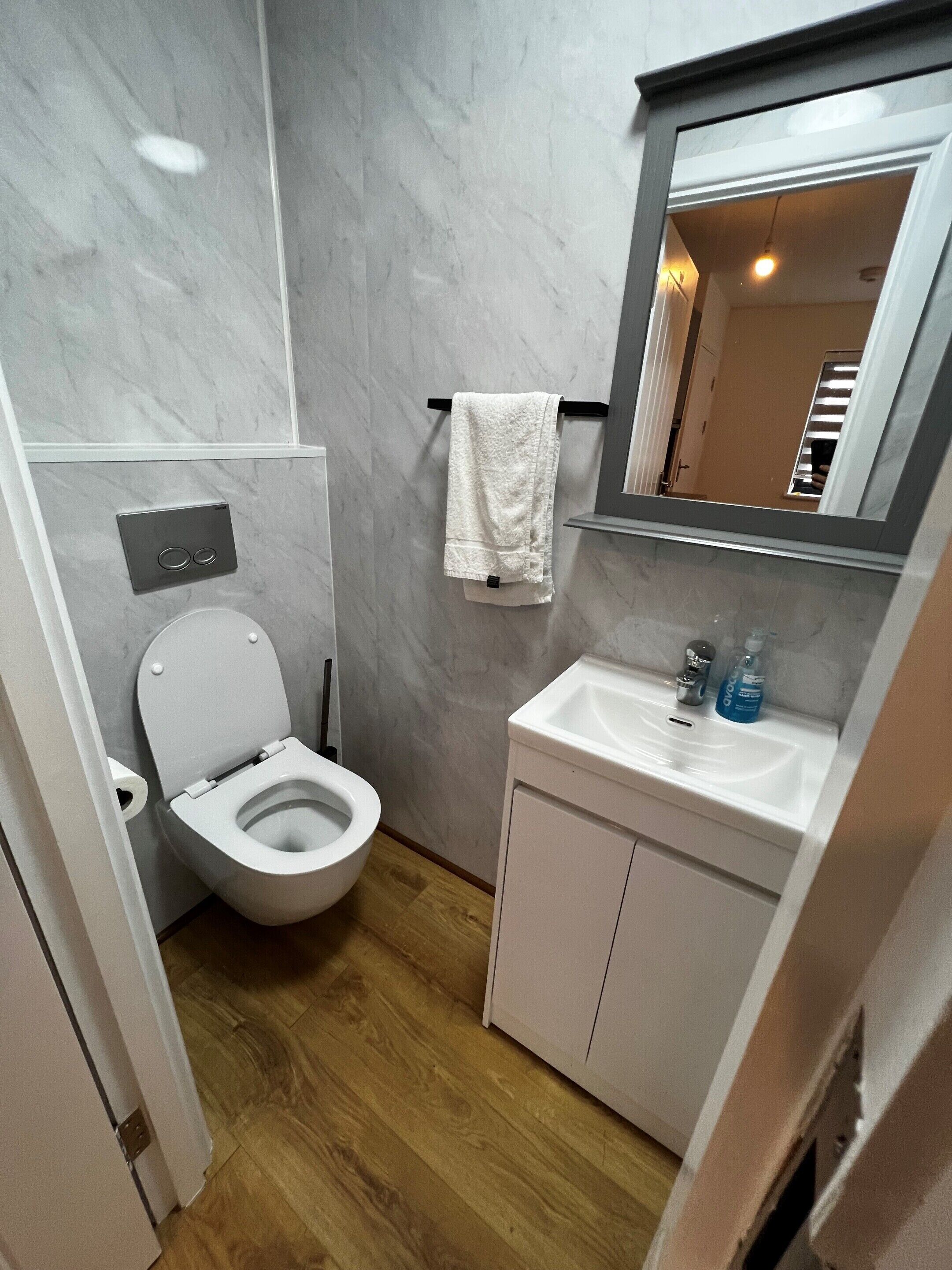 A modern bathroom with a toilet, sink, and mirror.