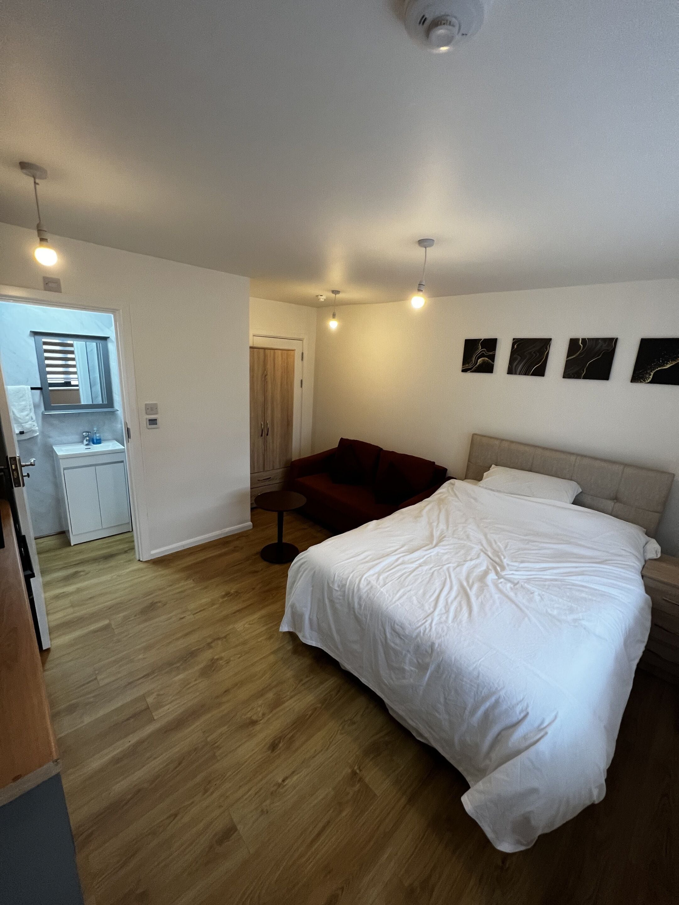 A bedroom with a large bed, a red sofa, a small table, and a wardrobe.