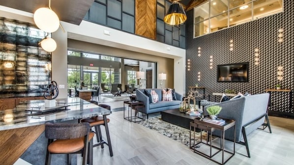 A spacious living area with a modern kitchen, a large sofa, and a dining area with bar stools.