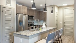 A modern kitchen with granite countertops, stainless steel appliances, and pendant lighting. - Landing | Stylish 2BD, Clubhouse, Courtyard (Austin)