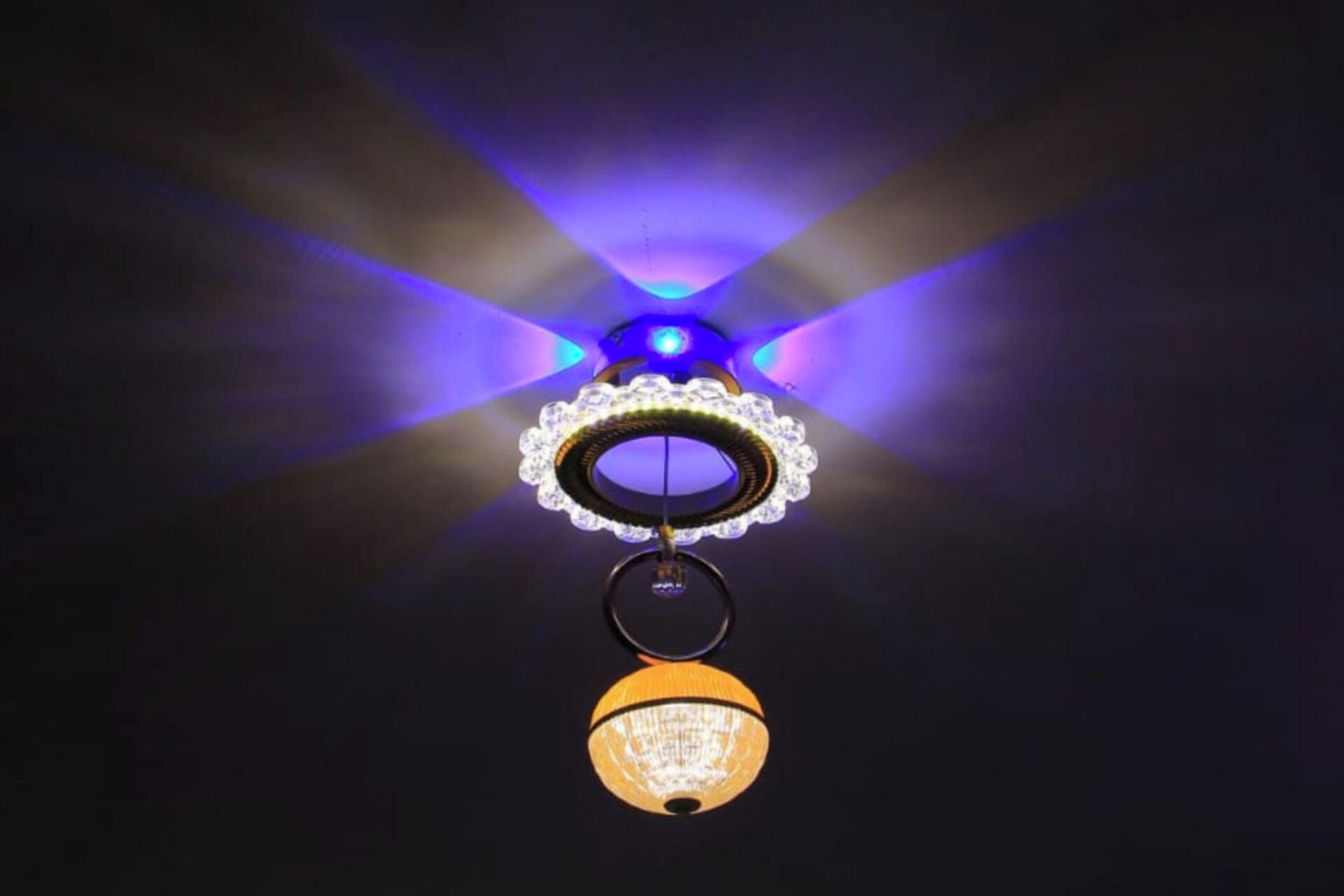 A ceiling with a central circular light fixture surrounded by a decorative ring, with additional lighting fixtures on either side.