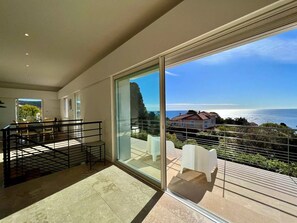 A modern interior with a large glass door leading to a balcony with a scenic ocean view. - Villa Avec Piscine, Plage et Crique à Pied, 4 Chambres (Saint-Raphaël)