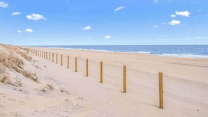 Ein sandiger Strand mit Holzpfählen und einem Seilzaun.