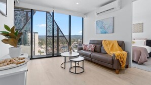 Sala moderna com uma grande janela, um sofá, uma mesa de centro e vista para a paisagem urbana.