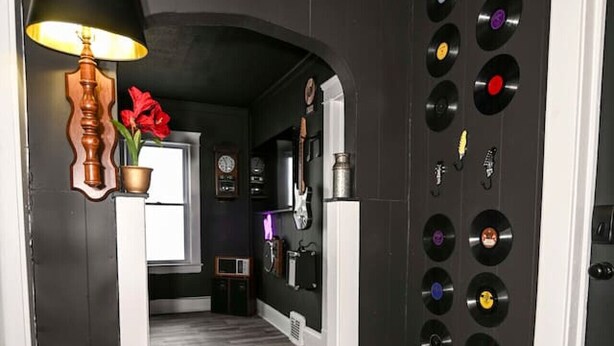 A hallway with a vinyl record on the floor, a lamp, and a wall decorated with vinyl records. - Cleveland’s Legends' Lair | Themed | Sleeps 4 (Cleveland)